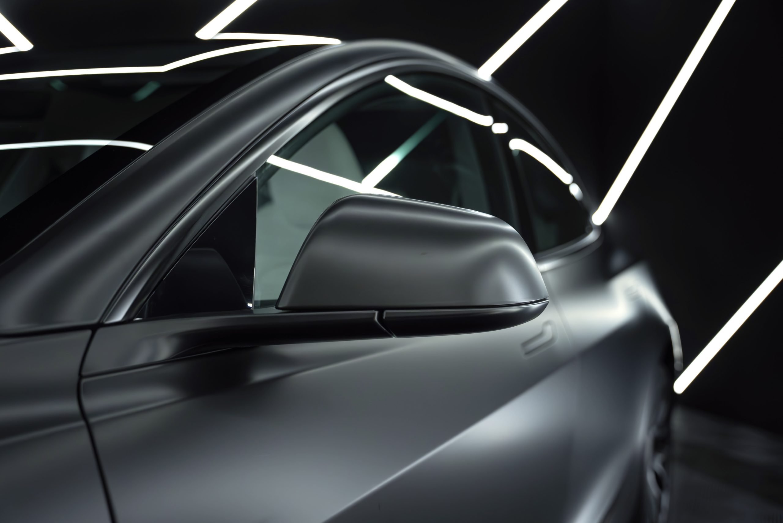 Close-up of the wing mirror of a black, dechromed car