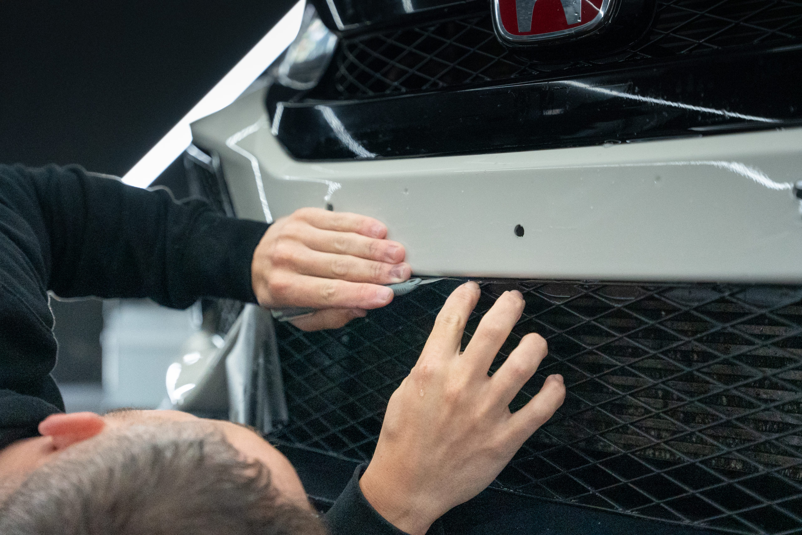 A man using a safety knife to cut around parts of a car