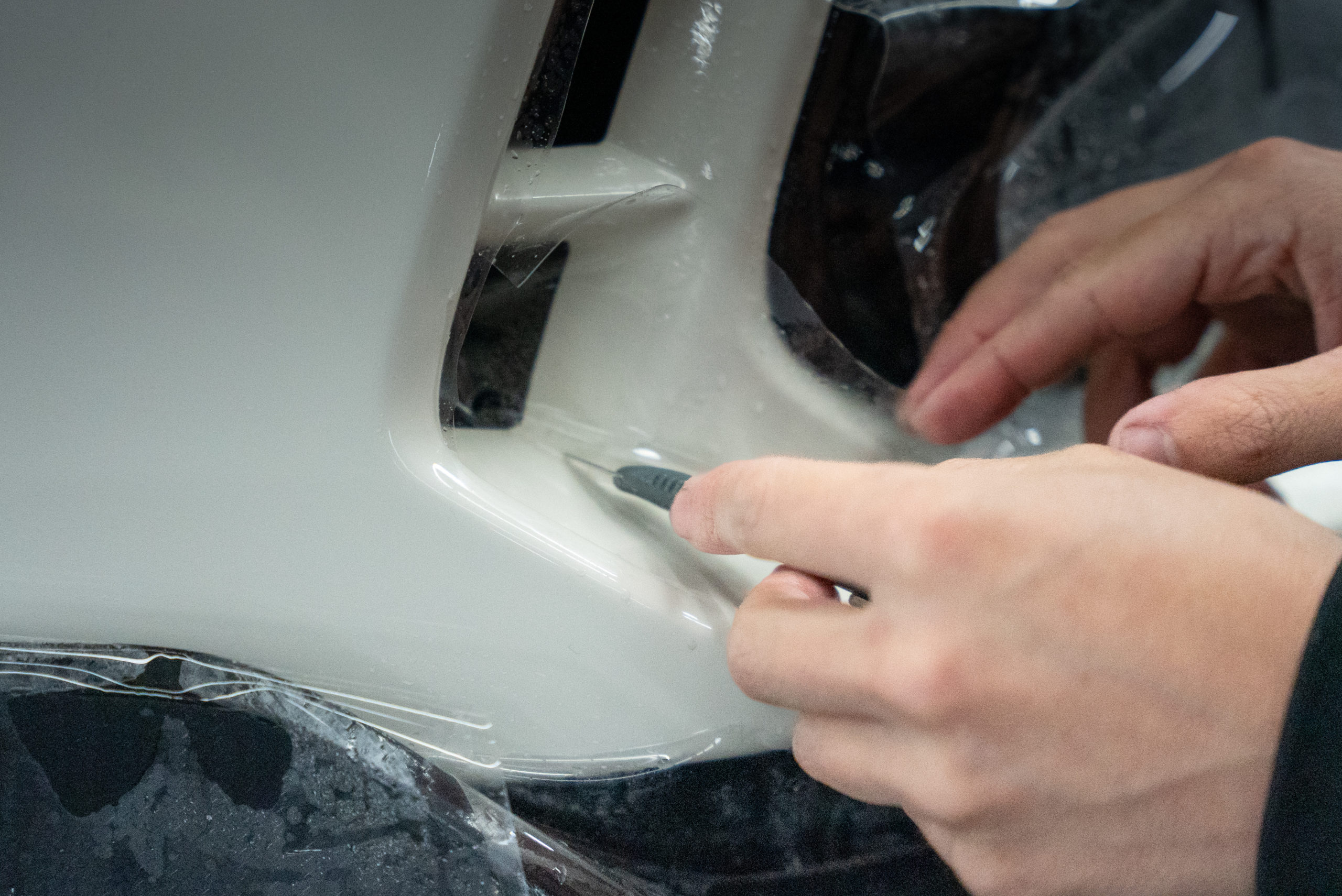 Close-up shot of someone cutting some Paint Protection Film on a car